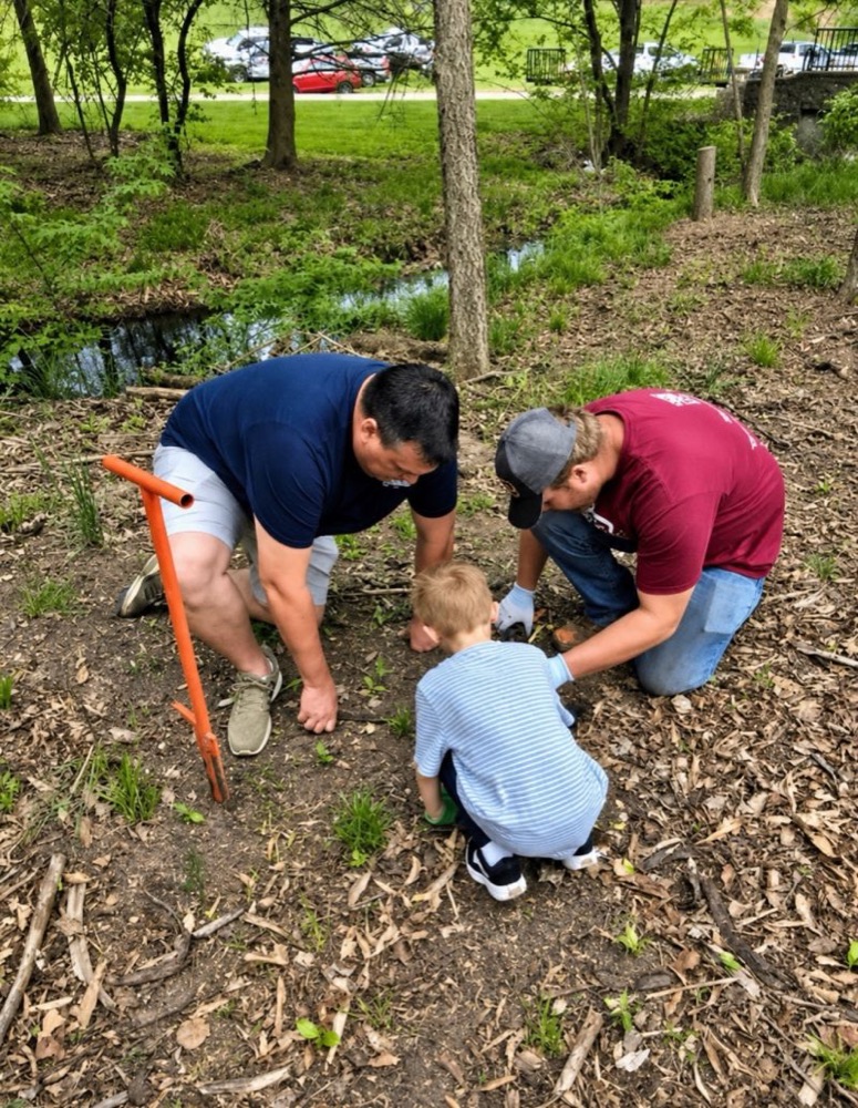 Associates and family planting a tree in the community