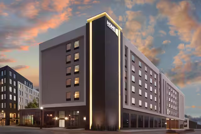 Home2 Suites urban exterior at dusk, in a downtown mixed-use context
